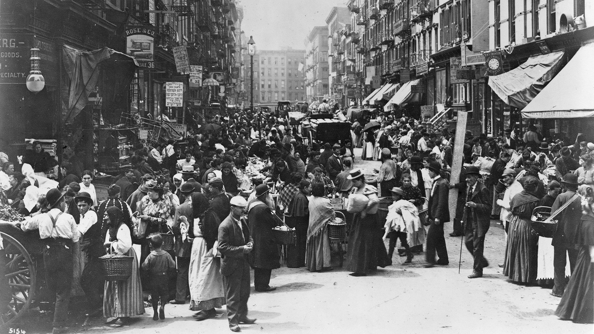 A crowded street on the Lower East Side in 1898. People are shopping from pushcarts and a majority of the signs are in Yiddish.