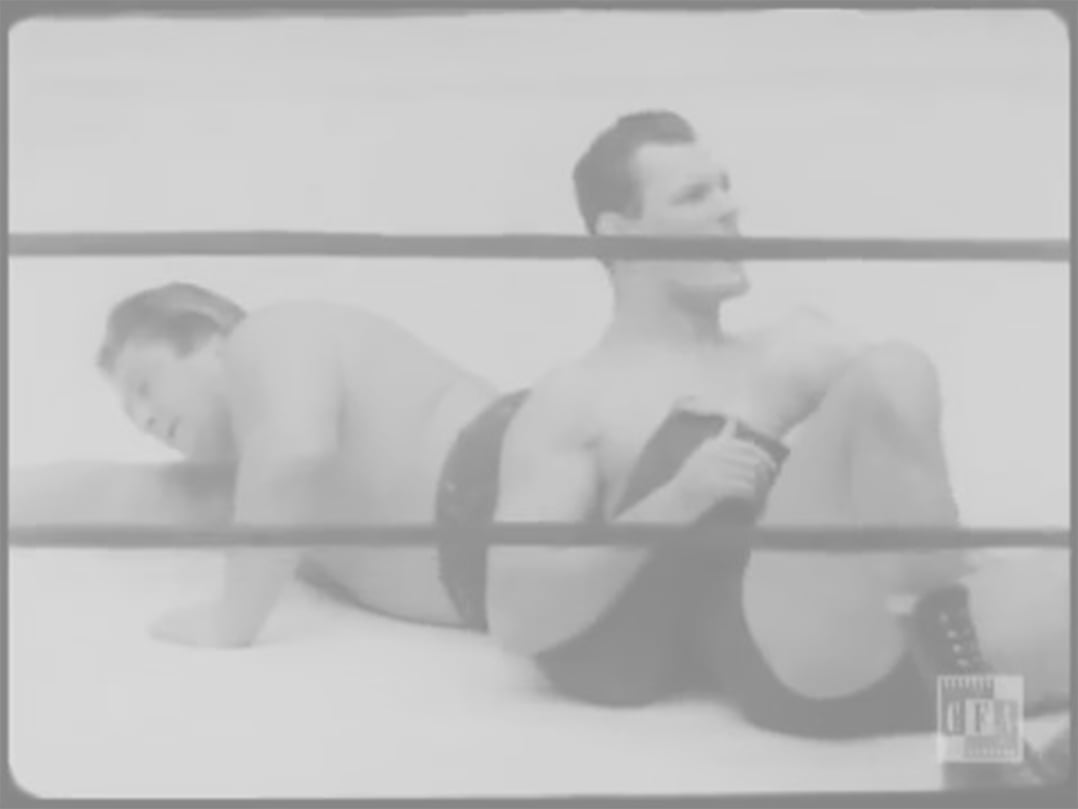 One man pinning another man in a wrestling ring.