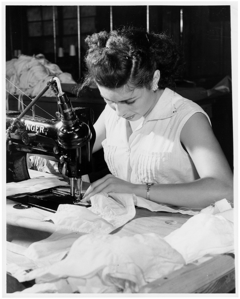 Young woman sewing on a Singer sewing machine. Black and white photo.