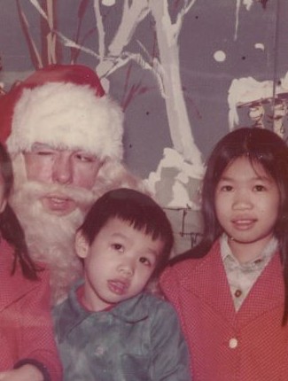Young Kevin and Alison sit with a winking Santa wearing a hat and fake beard.